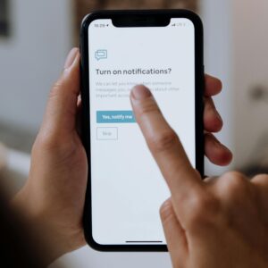 Close-up of hands using a smartphone for digital notification setup.